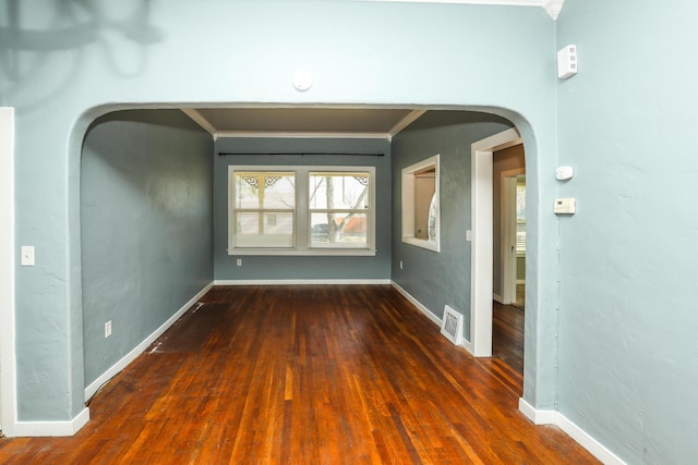 unfurnished room featuring visible vents, arched walkways, crown molding, and wood finished floors