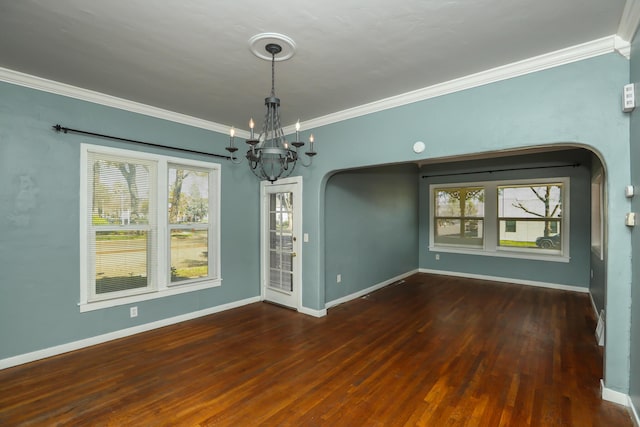 unfurnished dining area with ornamental molding, arched walkways, and wood finished floors