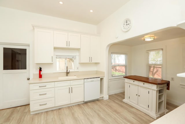 kitchen with light wood-style floors, white cabinets, white dishwasher, and a sink