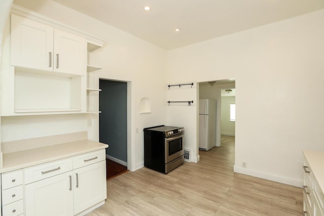 kitchen with electric stove, light countertops, open shelves, and freestanding refrigerator