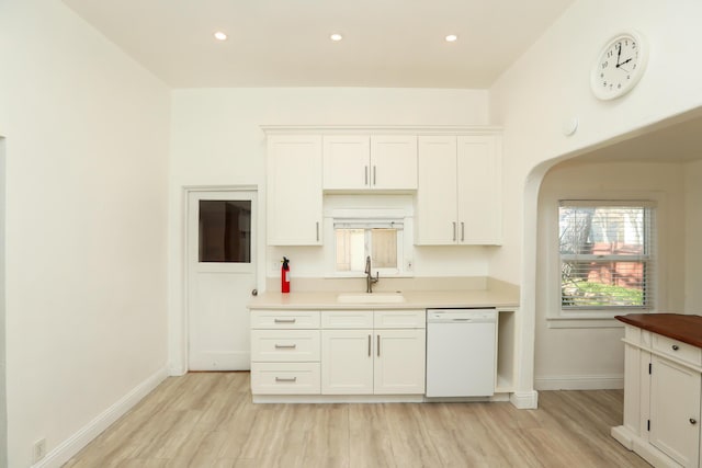 kitchen featuring white cabinets, baseboards, dishwasher, and a sink