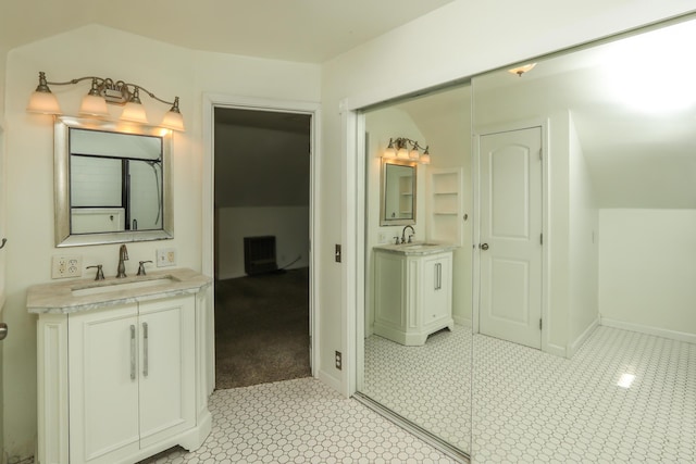 full bathroom featuring two vanities, a sink, and baseboards