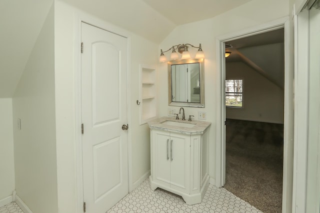 bathroom featuring vaulted ceiling, built in shelves, vanity, and baseboards