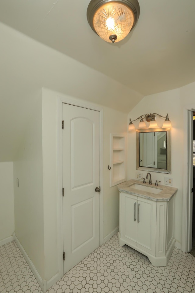 bathroom with lofted ceiling, baseboards, built in features, and vanity