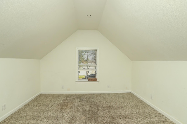 additional living space with carpet, lofted ceiling, baseboards, and a textured ceiling