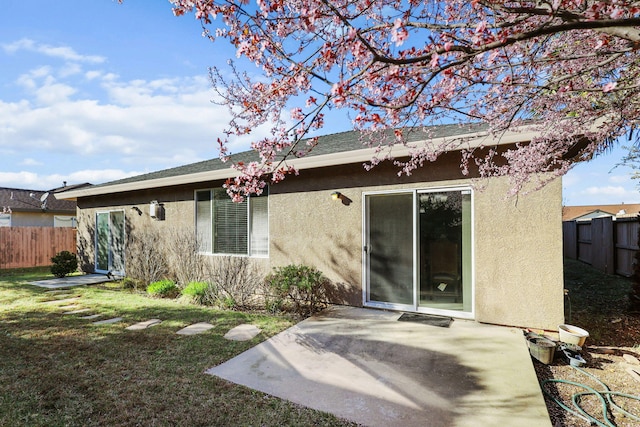 rear view of property with a patio, fence, and stucco siding