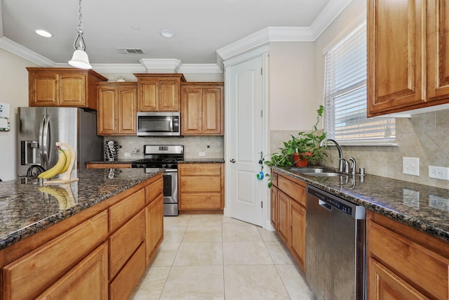 kitchen featuring appliances with stainless steel finishes, brown cabinets, dark stone countertops, a sink, and light tile patterned flooring