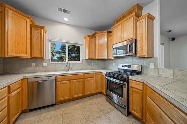 kitchen featuring appliances with stainless steel finishes, light tile patterned floors, visible vents, and tasteful backsplash