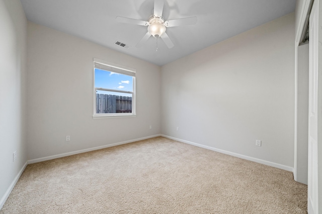 carpeted empty room with ceiling fan, visible vents, and baseboards