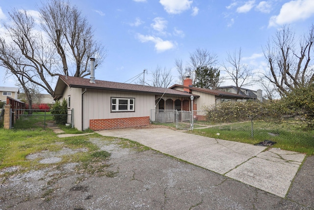 view of front of property with brick siding, fence, driveway, a gate, and a chimney