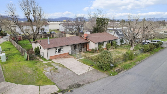 exterior space with a mountain view, fence, concrete driveway, roof with shingles, and a residential view