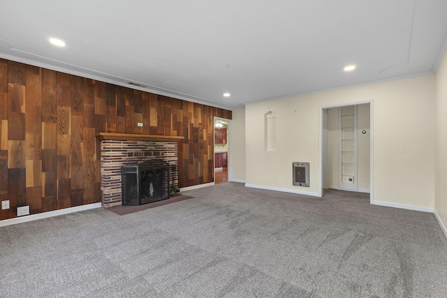 unfurnished living room featuring wooden walls, visible vents, heating unit, carpet floors, and a brick fireplace