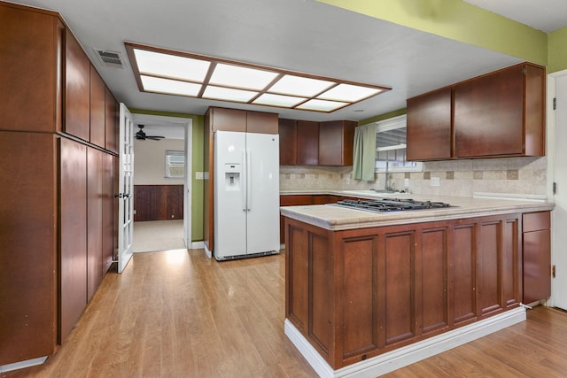 kitchen with light countertops, visible vents, stainless steel gas stovetop, white fridge with ice dispenser, and a peninsula