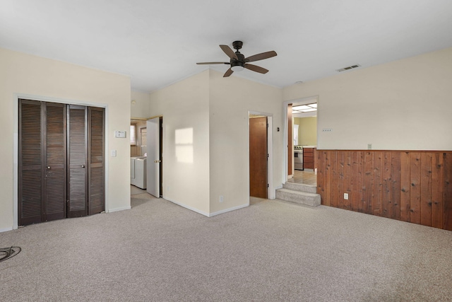 unfurnished bedroom with light carpet, wainscoting, visible vents, and wooden walls