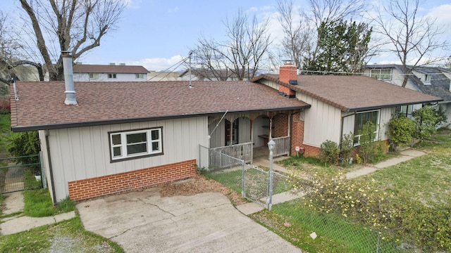 ranch-style home with brick siding, fence, a chimney, and roof with shingles