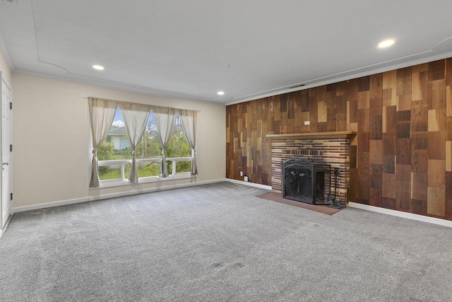 unfurnished living room featuring carpet floors, a fireplace, ornamental molding, wooden walls, and baseboards