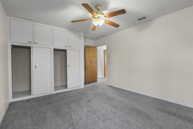 unfurnished bedroom with a closet, visible vents, a ceiling fan, carpet flooring, and a textured ceiling