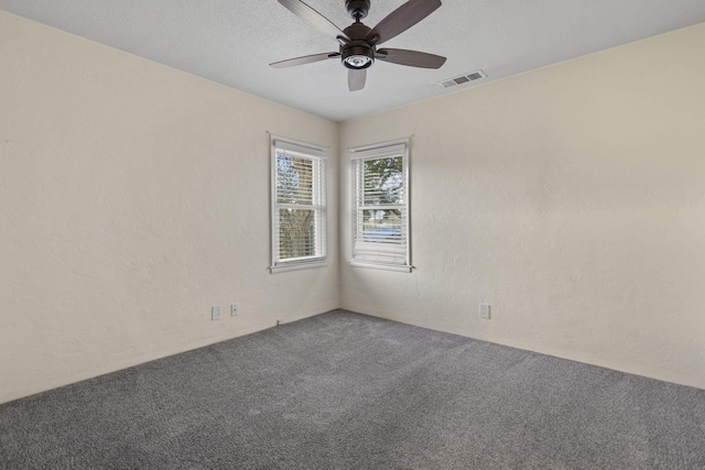 carpeted empty room featuring a ceiling fan, visible vents, a textured wall, and a textured ceiling