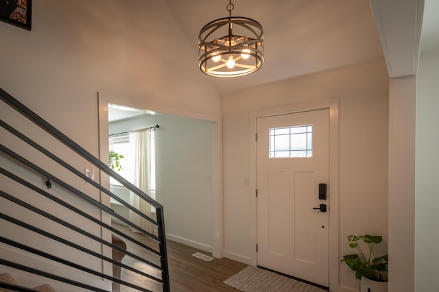 foyer featuring a chandelier, dark wood-type flooring, visible vents, vaulted ceiling, and stairway