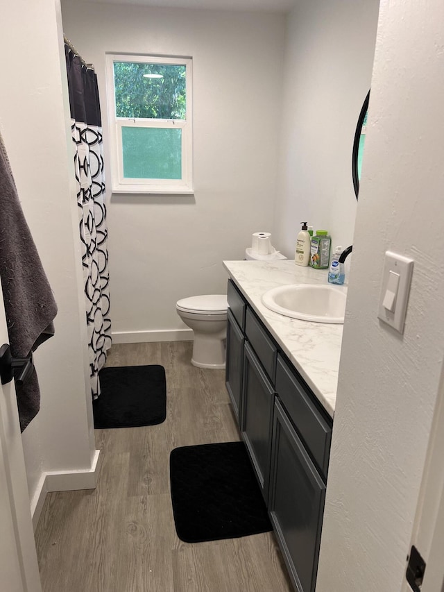 bathroom featuring wood finished floors, vanity, baseboards, toilet, and a shower with shower curtain