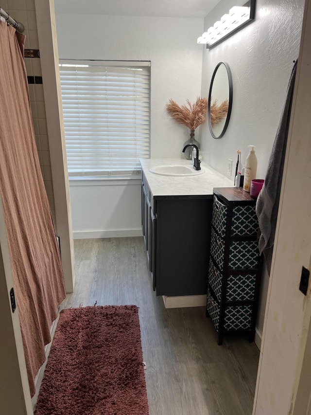 bathroom featuring baseboards, curtained shower, wood finished floors, and vanity