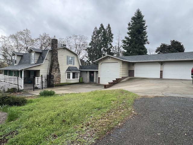 view of front of home featuring an attached garage, fence, driveway, a front lawn, and a chimney