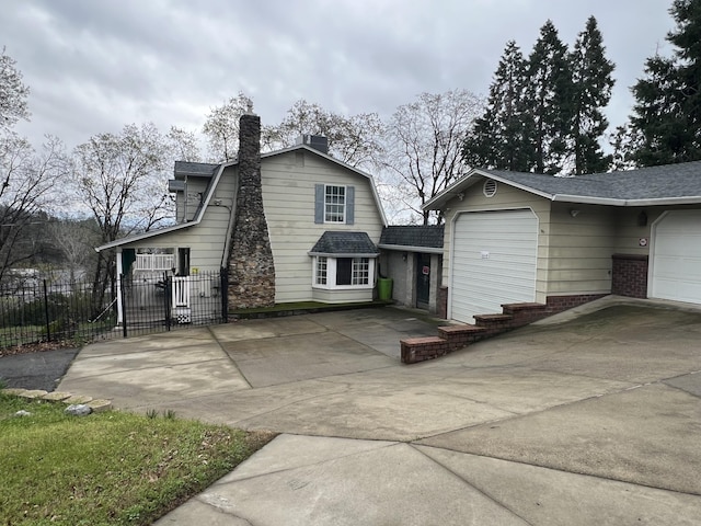 back of house featuring brick siding, a chimney, a gambrel roof, fence, and driveway