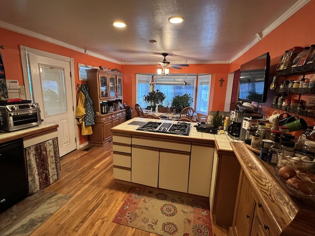 kitchen with black dishwasher, crown molding, tile countertops, stovetop with downdraft, and light wood-type flooring