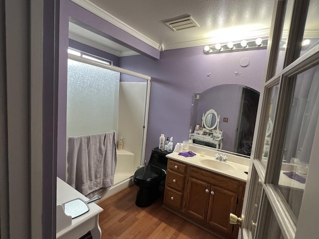 bathroom featuring wood finished floors, vanity, visible vents, a stall shower, and crown molding