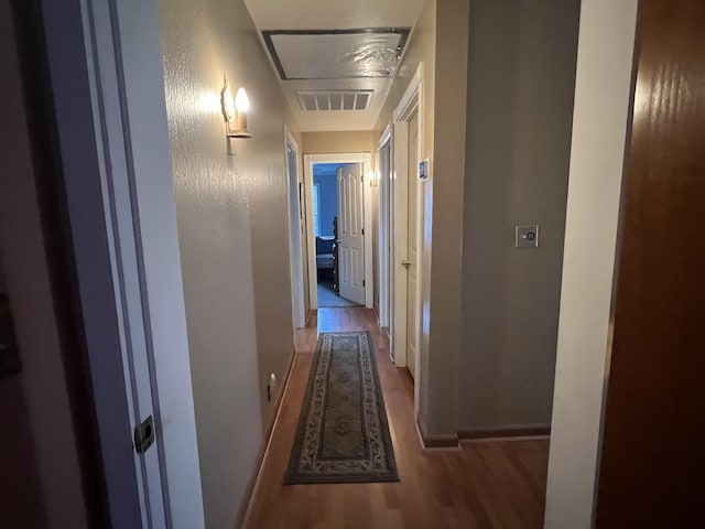 corridor with wood finished floors, visible vents, and baseboards