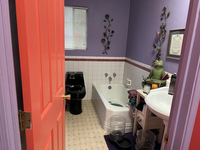 bathroom with tile walls, toilet, a wainscoted wall, tile patterned floors, and a bath