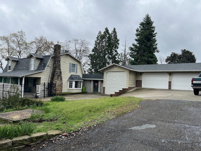 view of front of property featuring a garage, fence, a gambrel roof, driveway, and a chimney