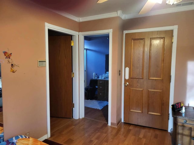 bedroom with baseboards, wood finished floors, visible vents, and crown molding