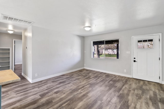 unfurnished living room featuring wood finished floors, visible vents, and baseboards