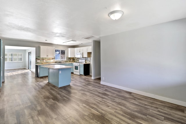 kitchen with white appliances, tasteful backsplash, visible vents, white cabinetry, and a sink