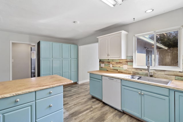 kitchen featuring light wood-style floors, dishwasher, light countertops, blue cabinetry, and a sink