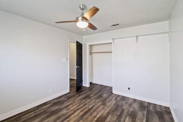 unfurnished bedroom with a closet, dark wood finished floors, visible vents, and baseboards