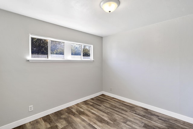 unfurnished room featuring dark wood-type flooring and baseboards