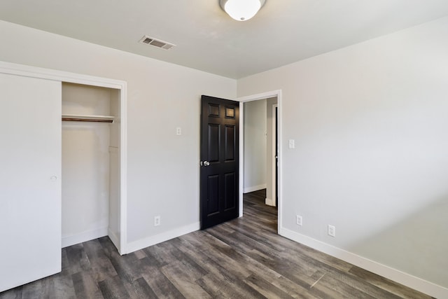 unfurnished bedroom with dark wood-style floors, a closet, visible vents, and baseboards