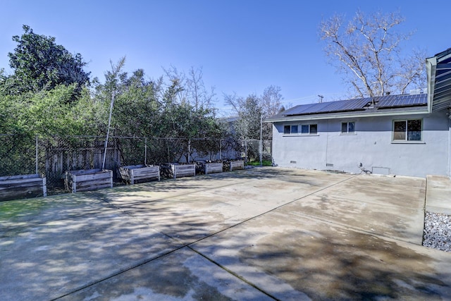 view of side of property featuring metal roof, solar panels, fence, crawl space, and a patio area