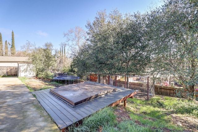 view of yard featuring a fenced backyard, a trampoline, a storage unit, a wooden deck, and an outdoor structure