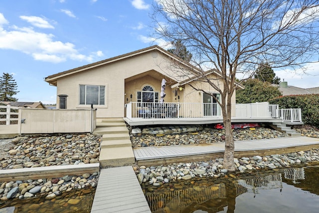 back of house with stairs, fence, a deck, and stucco siding