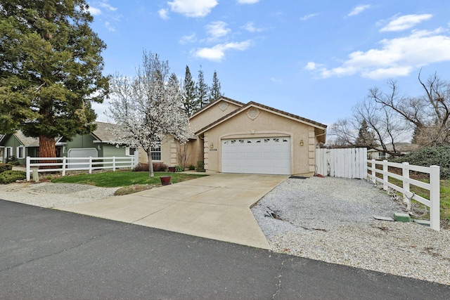 view of front of home with a fenced front yard, driveway, a garage, and stucco siding