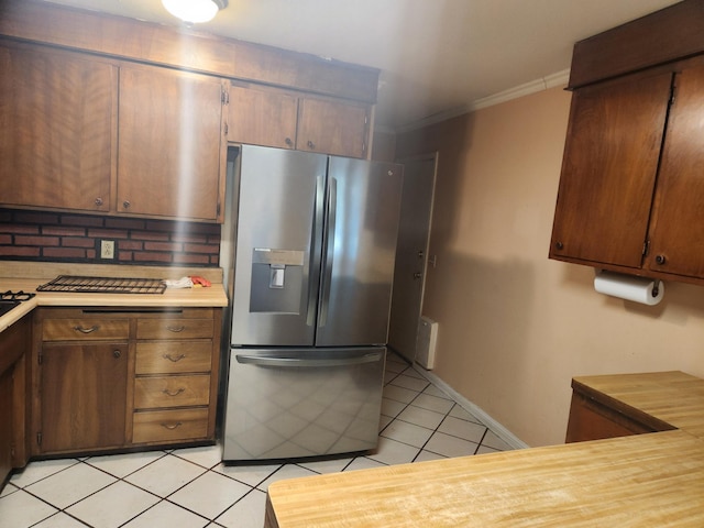 kitchen with light tile patterned floors, baseboards, light countertops, stainless steel fridge with ice dispenser, and crown molding