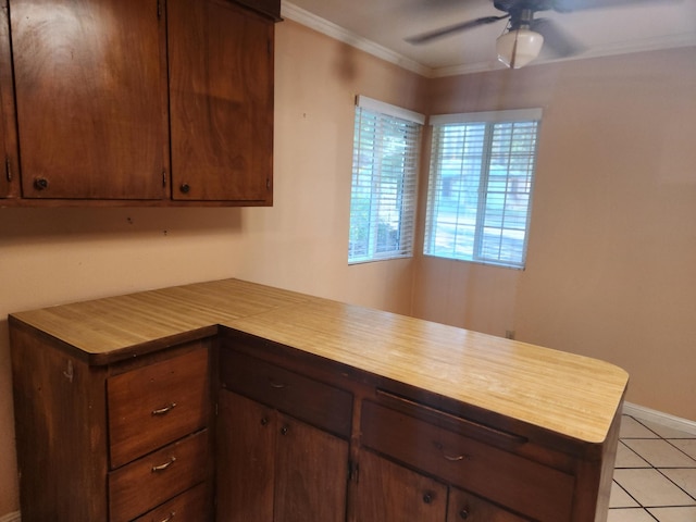 kitchen with light tile patterned floors, ornamental molding, ceiling fan, a peninsula, and baseboards