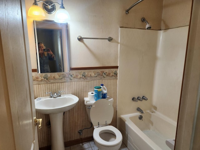 bathroom featuring shower / bathtub combination, tile patterned flooring, toilet, a sink, and wainscoting