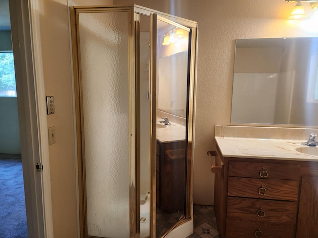 full bath featuring a textured wall, vanity, and a shower stall