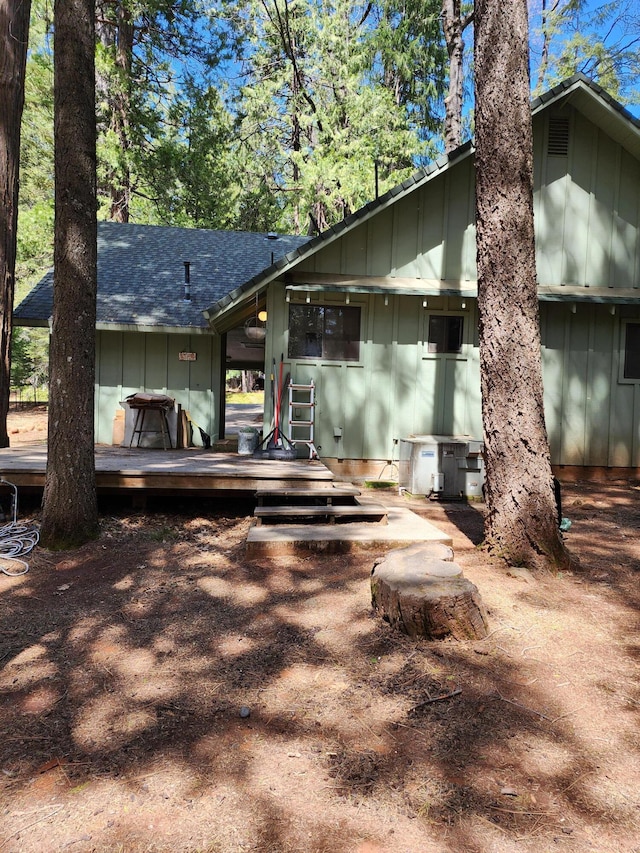 back of property featuring a deck, board and batten siding, and roof with shingles