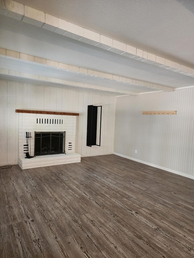 unfurnished living room with a brick fireplace, wood finished floors, and baseboards