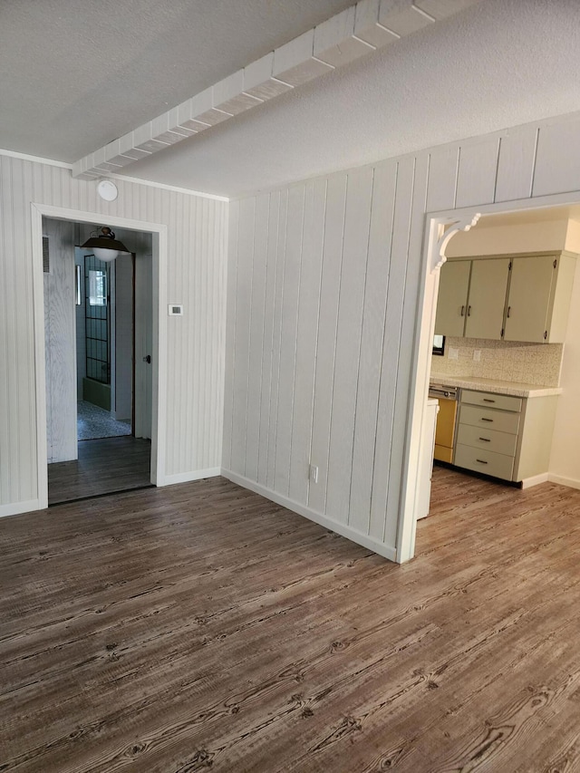 empty room with a textured ceiling, dark wood-type flooring, and baseboards